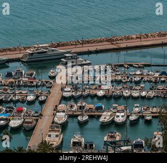 Molo pieno di barche e yacht di diverse forme e dimensioni sul mare. Foto Stock