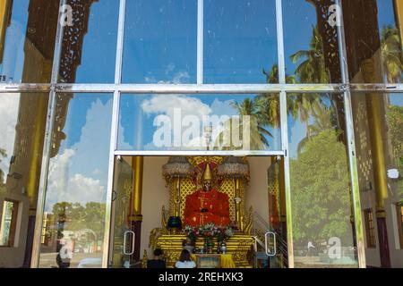 Rangoon, Myanmar, 2014. Specchi e riflessi alla Pagoda di Botahtaung, con persone che pregano di fronte a un'immagine di Buddha Foto Stock