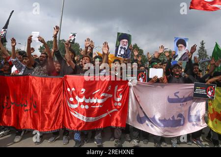 Gli sciiti del Kashmir in lutto tengono cartelli e il Corano mentre prendono parte a una processione Muharram a Srinagar, la capitale estiva del Kashmir amministrato dagli indiani, il 27 luglio 2023. Le autorità del Kashmir amministrato dagli indiani per la prima volta in oltre trent'anni permisero le processioni dal centro della città di Srinagar sull'ottavo Muharram, il primo mese del calendario lunare islamico. Le processioni Muharram furono bandite dal centro della città nel 1989 allo scoppio dell'insurrezione armata nella regione, anche se gli sciiti usavano portare fuori le processioni all'interno delle località e nelle periferie. (Foto di Sajad Foto Stock