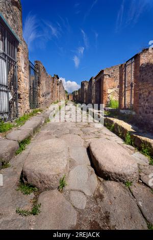 Strada lastricata in pietra tra le rovine dell'antica città romana di Pompei vicino a Napoli, Italia, distrutta dal vulcano Vesuvio nel 79 d.C. Immagine con prospettiva profonda Foto Stock