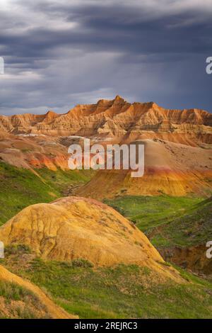 Il calore dei tramonti serali sulle Yellow Mounds, opportunamente chiamate, mentre i temporali si accumulano sulle cime erose del Badlands National Park del South Dakota. Foto Stock