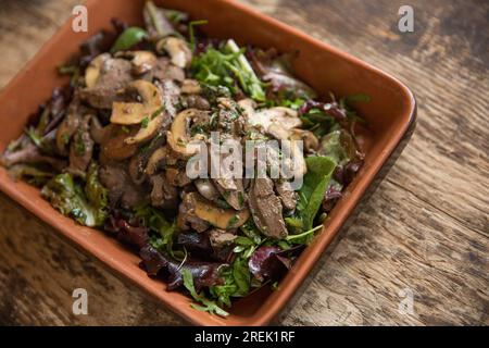 Fegati di pollo britannici fritti e serviti con funghi di castagno importati dalla Polonia, prezzemolo dalla Germania, basilico dall'Etiopia e catrame Foto Stock