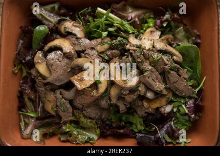 Fegati di pollo britannici fritti e serviti con funghi di castagno importati dalla Polonia, prezzemolo dalla Germania, basilico dall'Etiopia e catrame Foto Stock