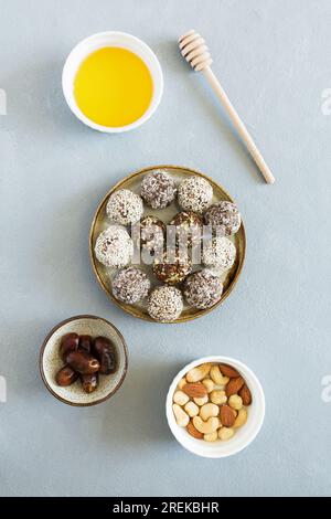 Le palline energetiche dolci con noci, frutta secca e miele in piatto piatto sono appoggiate su uno sfondo chiaro. Cibo vegetariano e biologico Foto Stock