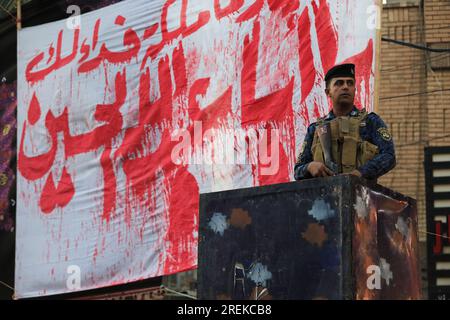 Baghdad, Iraq. 28 luglio 2023. Un agente di polizia sta di guardia durante una cerimonia rituale il giorno di Ashura a Kadhimiya. Ashura è il decimo giorno di Muharram, il primo mese del calendario islamico, che segna il giorno in cui Husayn ibn Ali, nipote del profeta islamico Maometto, fu ucciso nella battaglia di Karbala. Credito: Ameer al-Mohammedawi/dpa/Alamy Live News Foto Stock