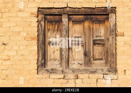 Khansahib Tehsil, Jammu e Kashmir, India. Finestra con persiane in legno su un muro di mattoni gialli. Foto Stock