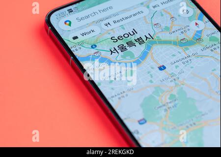 New York, USA - 21 luglio 2023: Distribuzione del traffico automobilistico di Seoul su google Maps su uno schermo dello smartphone vista ravvicinata con sfondo rosso Foto Stock