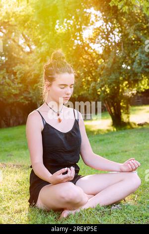 La bella adolescente medita nella natura Foto Stock