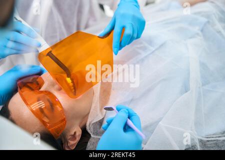 Il dentista inserisce un riempimento fotopolimerico sul paziente Foto Stock