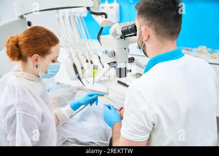 Il medico dentista e il suo assistente dai capelli rossi sul posto di lavoro Foto Stock