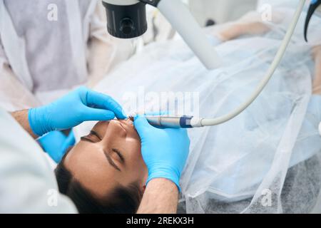 Il medico in una clinica dentale riempie un dente per il cliente Foto Stock