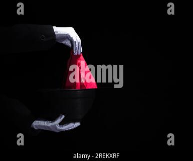 La mano del mago esegue un trucco magico con un cappello nero con tovagliolo. Foto ad alta risoluzione Foto Stock