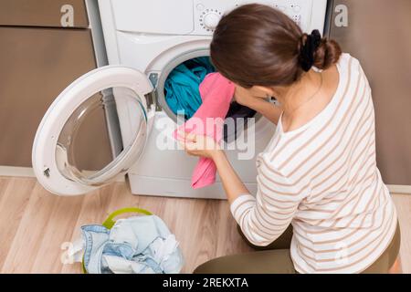 Signora che porta i vestiti fuori dalla lavatrice. Foto ad alta risoluzione Foto Stock