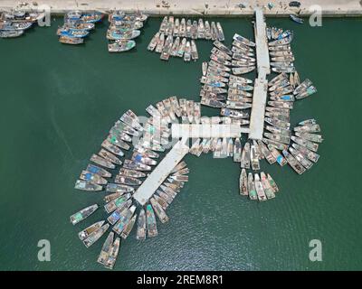 YANTAI, CINA - 28 LUGLIO 2023 - le barche da pesca impegnate nell'agricoltura offshore tornano al porto per ripararsi dal vento al porto di pesca di Dongkou Foto Stock
