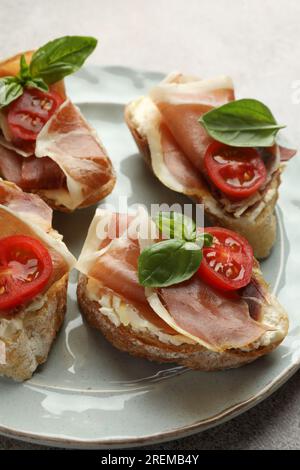 Gustosi panini con prosciutto stagionato, basilico e pomodori su piatto, primo piano Foto Stock