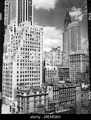 New York, New York: c. 1940 New York City vista da Madison Avenue con il famoso Chrysler Building sullo sfondo. I grattacieli contrastano con gli edifici più piccoli degli appartamenti e con le loro iconiche piazze di fronte. Foto Stock