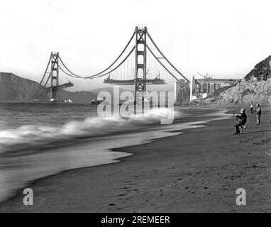 San Francisco, California: c.1936. I pescatori di Baker Beach apprezzeranno la vista del Golden Gate Bridge, in costruzione. Foto Stock