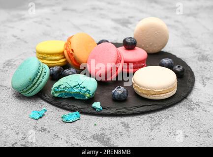 Tavola con dolci macaron e mirtilli su sfondo grigio Foto Stock