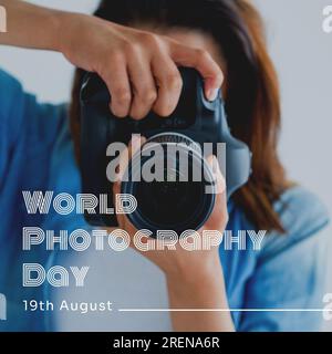 Testo e data del giorno della fotografia mondiale in bianco su donna birazziale che usa la fotocamera Foto Stock