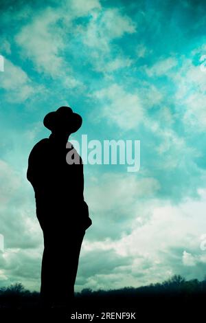 silhouette di un uomo che indossa un cappello davanti a un cielo nuvoloso Foto Stock