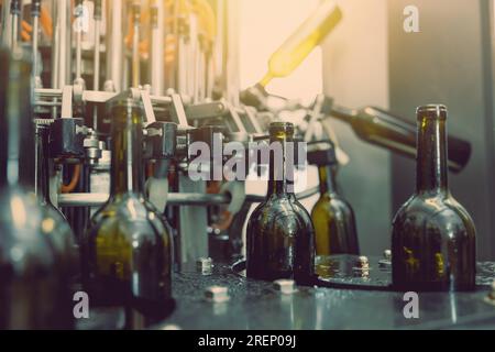 primo piano della macchina per la pulizia dell'iniezione di acqua in bottiglia di vino scuro in funzione in una fabbrica vinicola Foto Stock