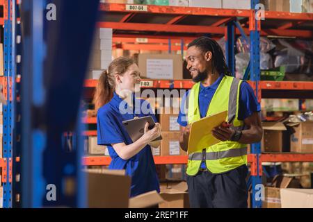 addetto all'inventario del magazzino felice di lavorare insieme un amico del team diversity presso i depositi di prodotti cargo Foto Stock