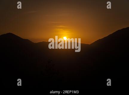 Il sole sorge sulla cresta montuosa dell'Himalaya, creando sagome di picco. Stock media, Uttarakhand, India. Foto Stock