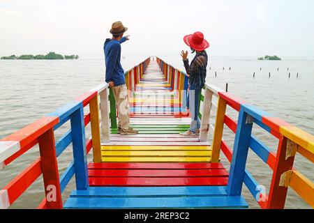 Coppia felice che si rilassa insieme su una passerella in legno multicolore Foto Stock