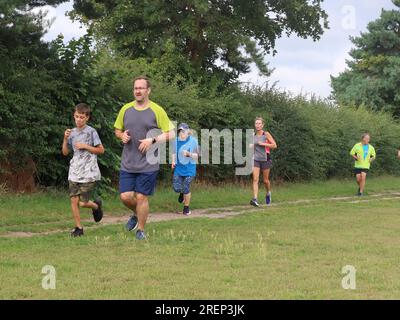 Kesgrave, Suffolk - 29 luglio 2023: Caldo estate sabato mattina Parkrun al Millennium Field. Un ragazzo che guida un gruppo. Foto Stock