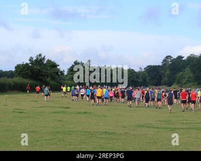 Kesgrave, Suffolk - 29 luglio 2023: Caldo estate sabato mattina Parkrun al Millennium Field. I corridori si dirigono verso la partenza. Foto Stock