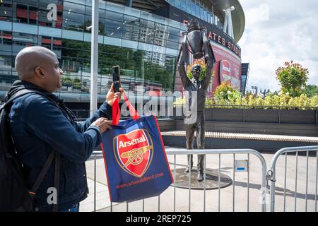 Londra, Regno Unito. 29 luglio 2023. Un tifoso vede la statua del manager dell'Arsenal Arsène Wenger che detiene il trofeo della Premier League che è stato installato all'esterno dell'Emirates Stadium il giorno precedente. Il leggendario allenatore guidò l'Arsenal FC a tre titoli di Premier League, tra cui la famosa stagione degli Invincibles nel 2003/04, dove la sua squadra rimase imbattuta, e sette fa Cup. Creata dallo scultore Jim Guy, la statua di bronzo è alta 3,5 m e pesa quasi mezza tonnellata. Crediti: Stephen Chung / Alamy Live News Foto Stock