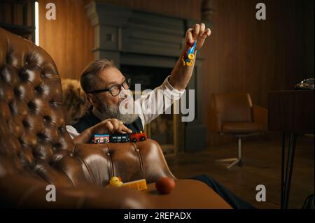 Divertente uomo d'affari anziano che gioca a giocattoli e si diverte dopo una dura giornata di lavoro Foto Stock