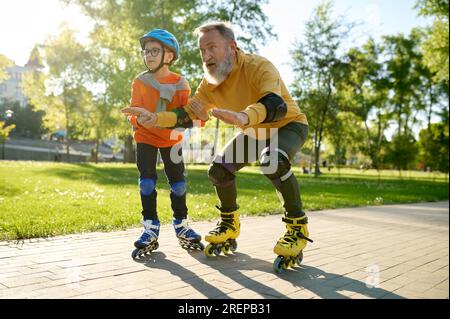 Bambino che insegna a suo padre a cavalcare pattini a rotelle nel parco Foto Stock