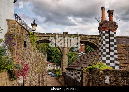 Gli archi del viadotto ferroviario attraversano una strada a Waterside, Knaresborough con un camino decorato bianco e nero, North Yorkshire, Inghilterra. Foto Stock