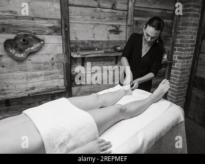 Massaggiatore che fa massaggio ai piedi con olio nel salone termale. Procedure del centro benessere. massaggio ai piedi rilassante e benessere. Concetto di cura del corpo. Terapia del piede femminile. Foto Stock