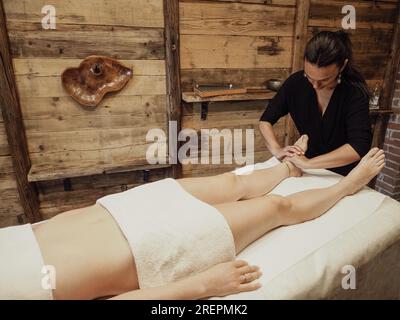 Massaggiatore che fa massaggio ai piedi con olio nel salone termale. Procedure del centro benessere. massaggio ai piedi rilassante e benessere. Concetto di cura del corpo. Terapia del piede femminile. Foto Stock