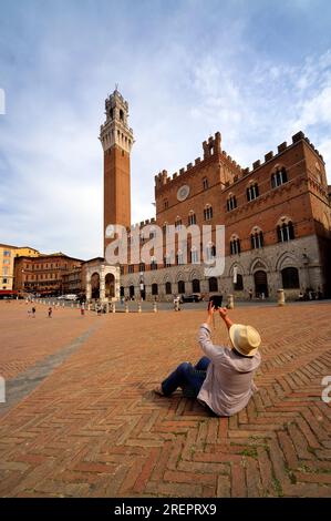 Siena, Italia - 10 settembre 2021: Un turista gode di Piazza del campo, Palazzo Publico e Torre del Mangia Siena, Italia. Foto Stock