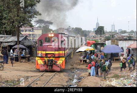 KENYA, Nairobi, Kibera slum, linea ferroviaria, treno merci, Dietro il grattacielo nel centro della città / KENIA, Nairobi, Kibera Slum, Bahnlinie, Güterzug Foto Stock