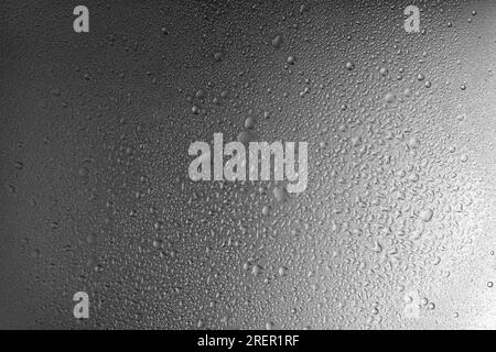 Gocce d'acqua su sfondo metallico grigio con passaggio fluido dell'illuminazione. Sfondo, carta da parati, superficie coperta da gocce d'acqua. Bolle di Foto Stock