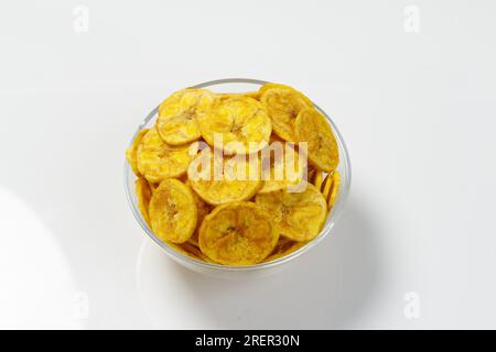Kerala chips o Banana chips, snack cult di Kerala, disposti in una ciotola trasparente; immagine isolata con sfondo bianco Foto Stock