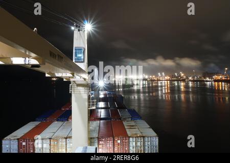 Nave container caricata con gru ancorate vicino al porto di Paranagua durante la notte con cielo coperto. Foto Stock