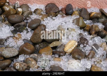 Pietre di grandine sparse per terra con pietre decorative. Foto Stock