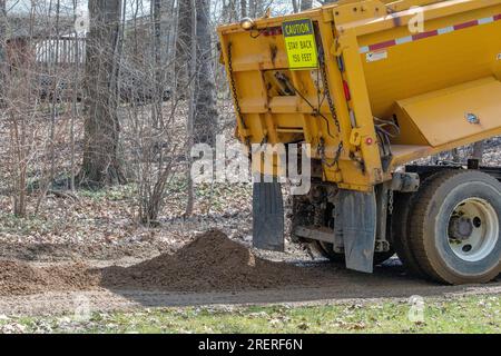 Un grande dumper scarichi lo sporco su una strada per la riparazione su strada Foto Stock