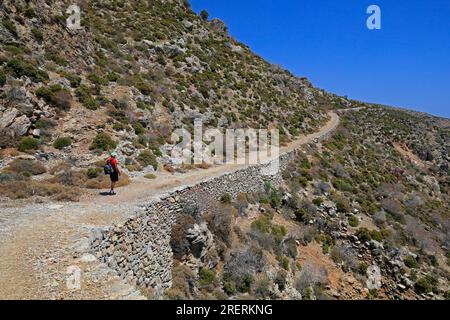 Camminatore solitario sul sentiero da Livadia alla spiaggia di Lethra lungo il sentiero roccioso di montagna, l'isola di Tilos, il gruppo di isole del Dodecaneso. Grecia, luglio 2023 Foto Stock