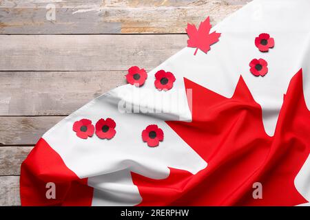 Bandiera del Canada e fiori di papavero su sfondo di legno. Giorno della memoria Foto Stock