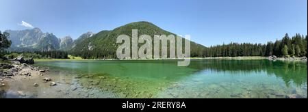 Vista panoramica delle acque turchesi del Lago Die Fusine superiore nelle Alpi Giulie dell'Italia nord-orientale con la parete rocciosa del Monte Mangart Foto Stock