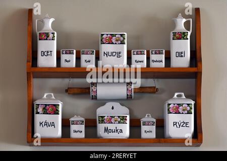 Contenitori da cucina vintage in ceramica esposti su scaffali in legno con motivi floreali ed etichette in lingua ceca Foto Stock