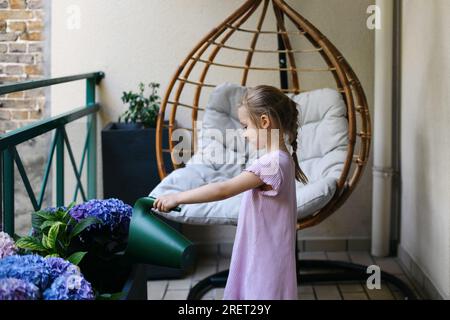 Una ragazza che annaffiava ortensie sul balcone Foto Stock