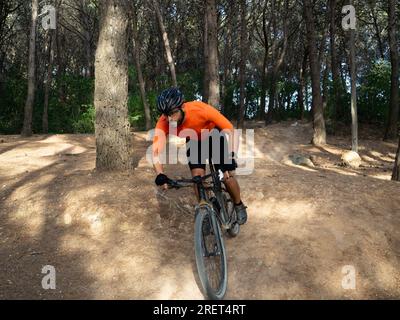 Uomo in mountain bike in mountain bike attraverso la foresta. Pista per mountain bike, attività sportive estreme Foto Stock