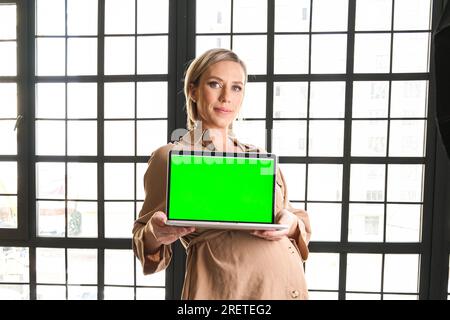 Un computer portatile con un'immagine a schermo verde su cui una ragazza incinta Foto Stock